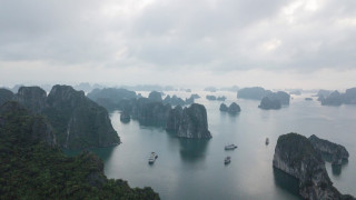 An array of small tropical islands with high cliffs and jungle on top. Boats sail between them.